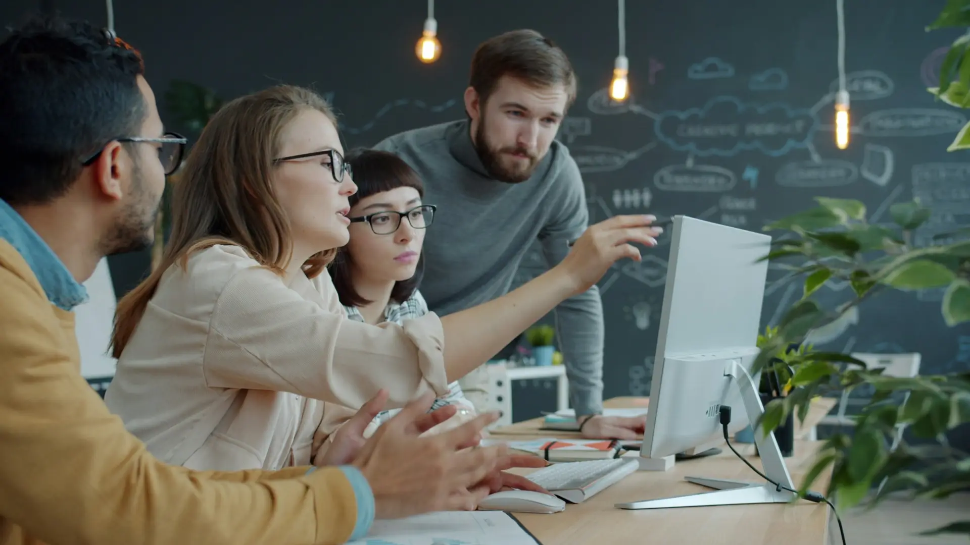 Colleghi che usano un software insieme davanti a un computer in ufficio